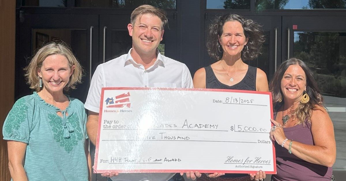 Cascades Academy staff members Homes for Heroes real estate specialist hold big check