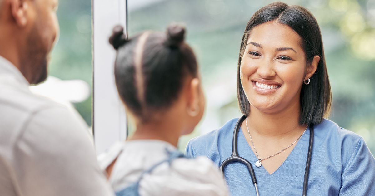 father child patient thanking nurse smiling in scrubs in clinic room