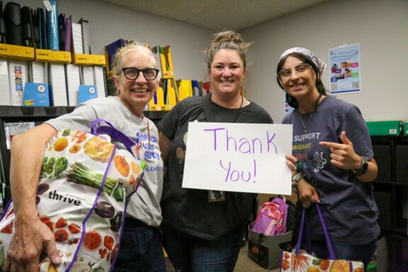 group of teachers at Educator Emporium picking up supplies holding sign thanking Homes for Heroes Foundation