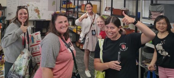 group teachers giving thumbs up choosing items from APS Foundation Educator Emporium