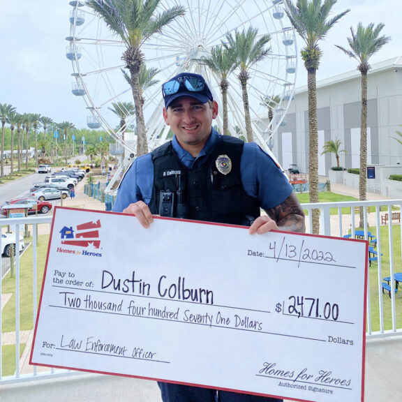 police officer holding big check money given back Homes for Heroes law enforcement appreciation
