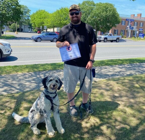 service member receives certification holding service dog on leash outside