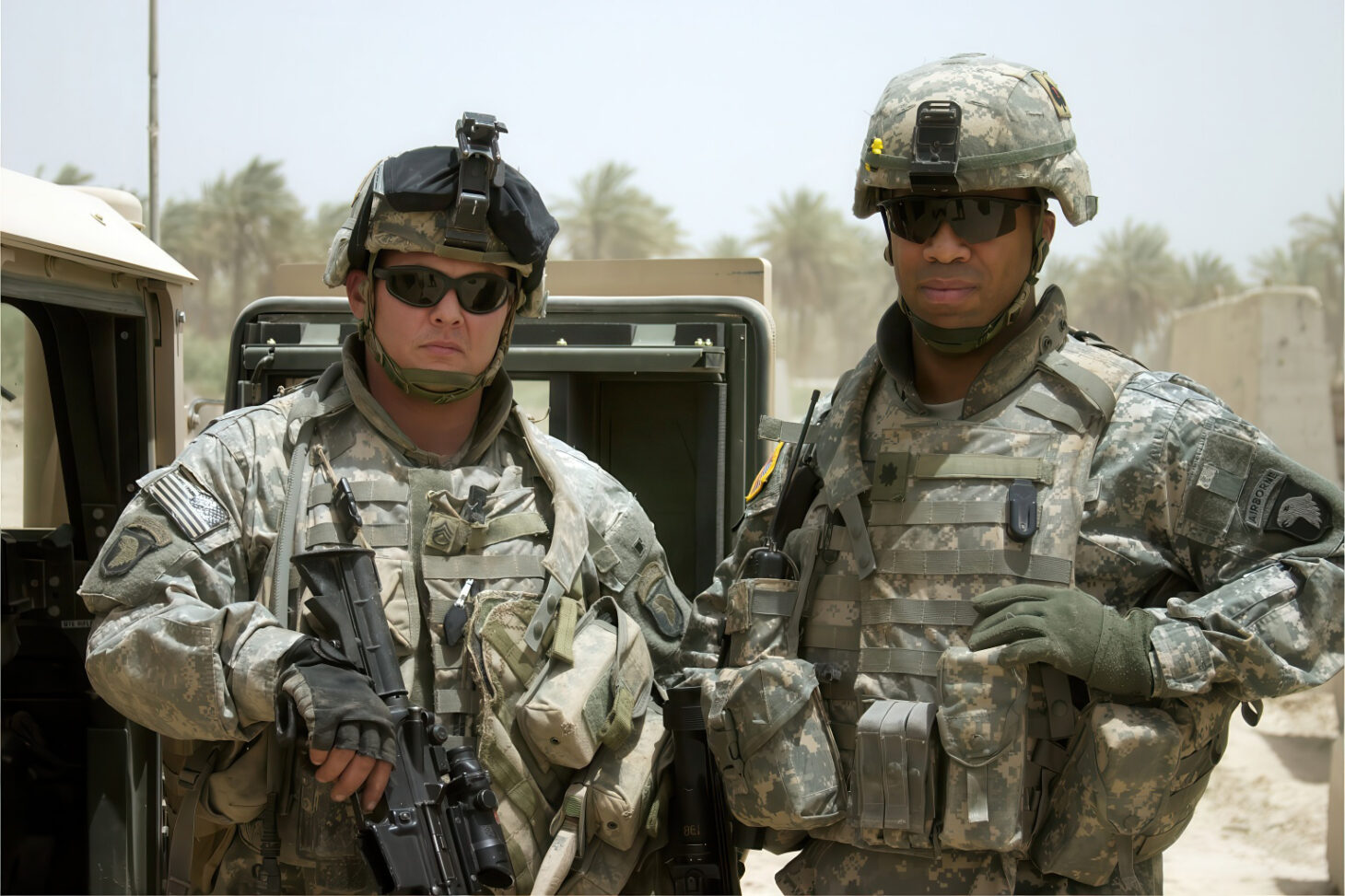 Two active-duty military members in gear by a Humvee