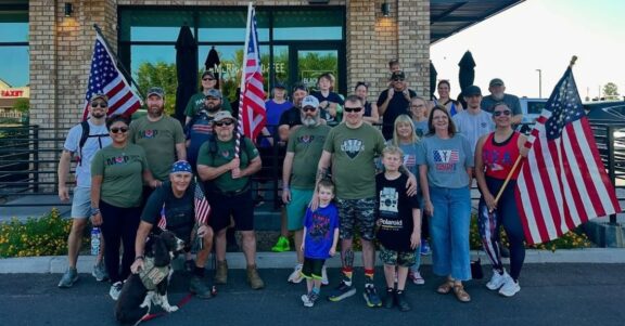 veteran group event supporting Home Record Project in front of black rifle coffee company holding US flags
