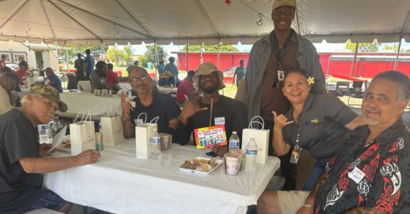 veterans gathered around table at usvets barbers point event under tent eating meal